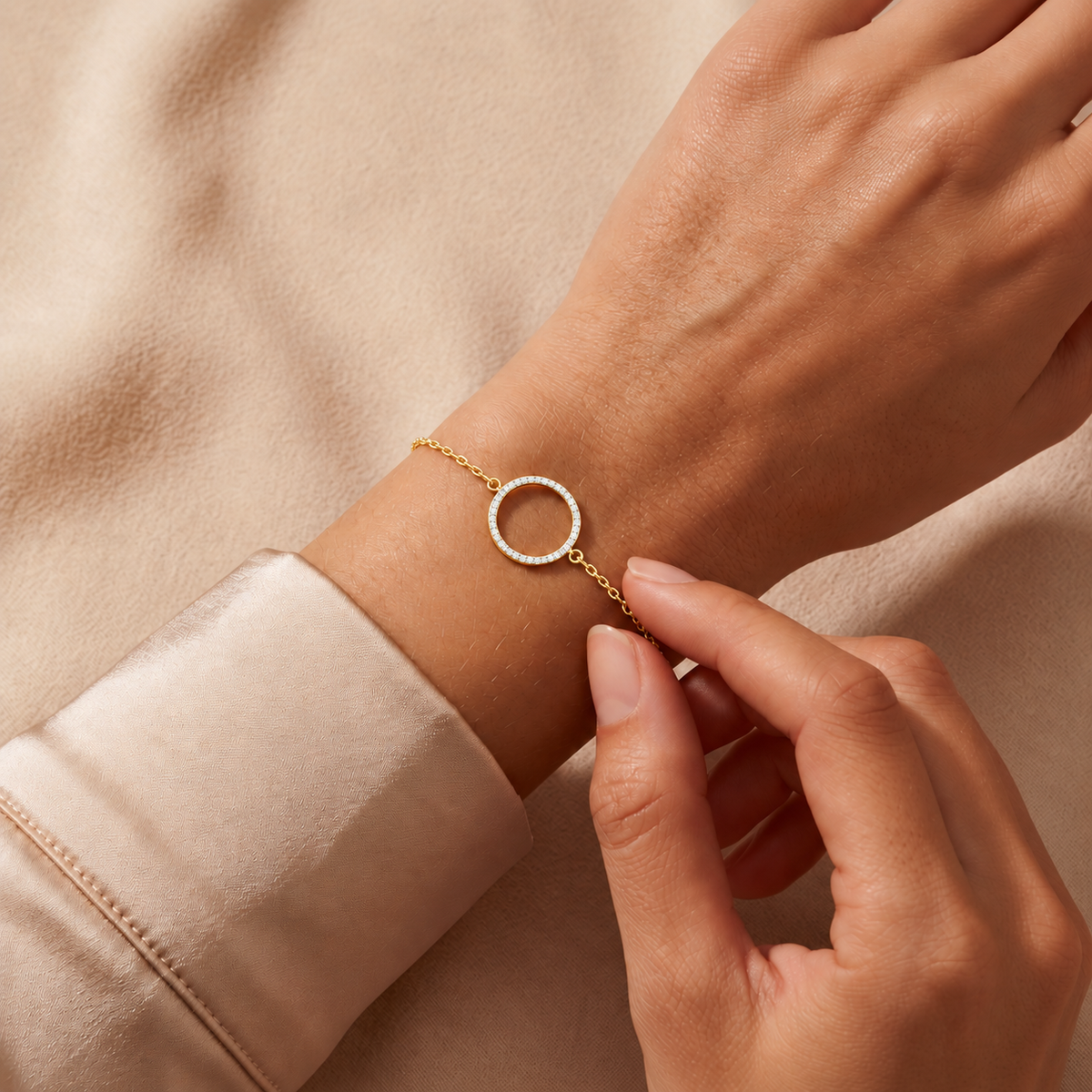 Yellow gold large pave circle diamond bracelet 105-10007 worn on a wrist against champagne satin and beige fabric