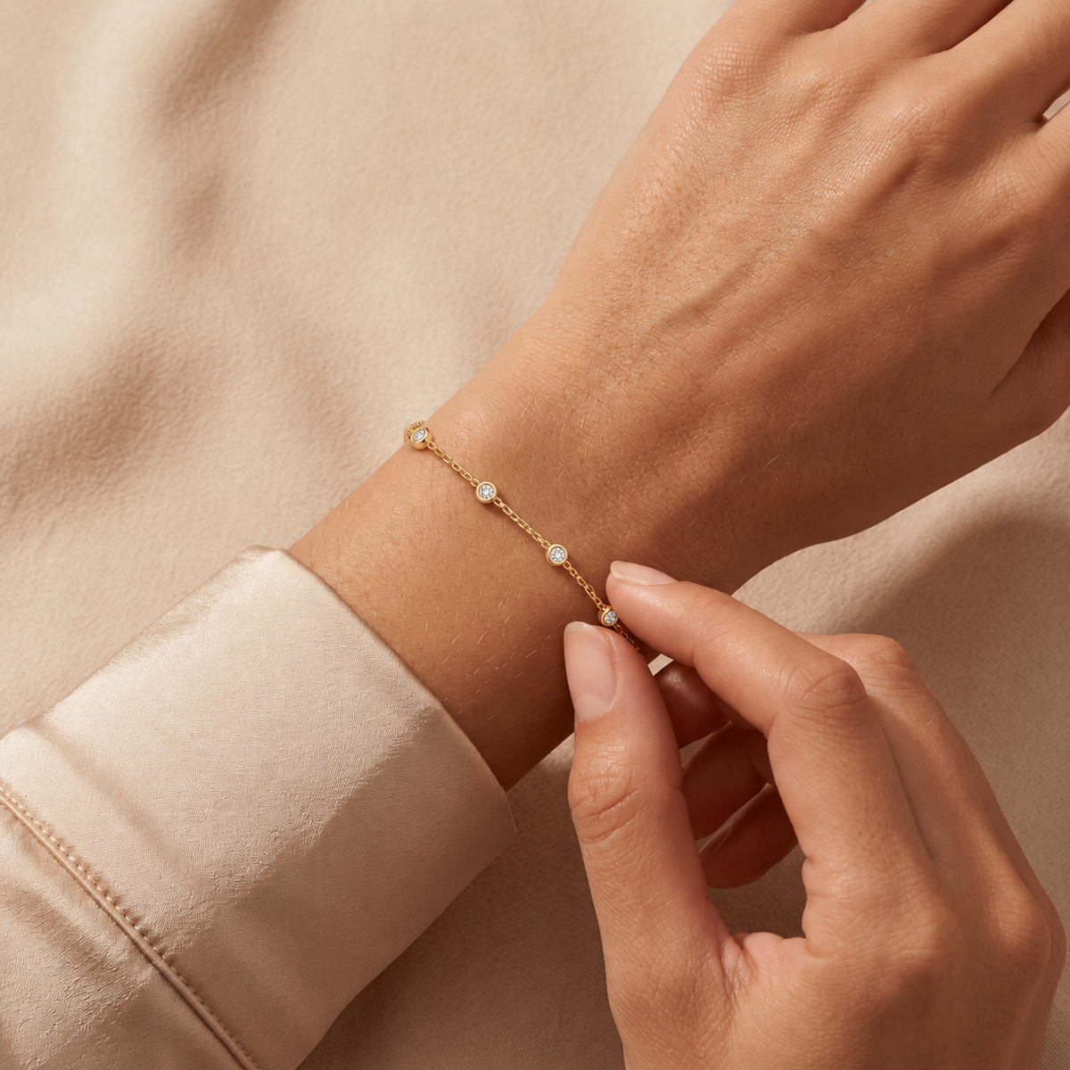 Yellow gold five station diamond bracelet 105-10008-5-1-4 worn on a wrist against champagne satin and beige fabric