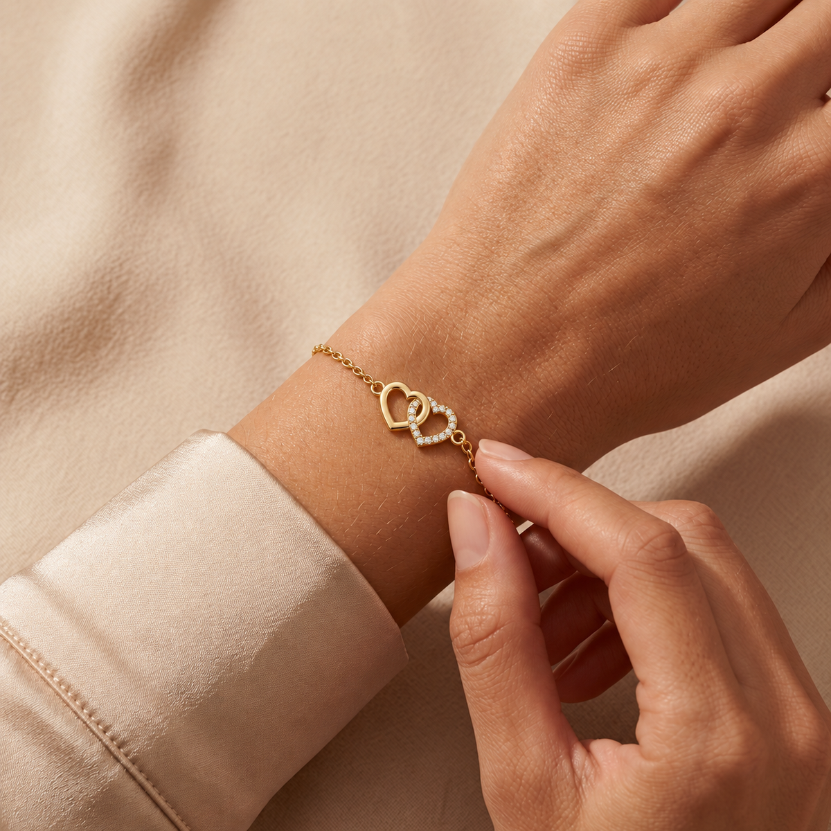 Yellow gold interlinked hearts diamond bracelet 105-10010 worn on a wrist against champagne satin and beige fabric