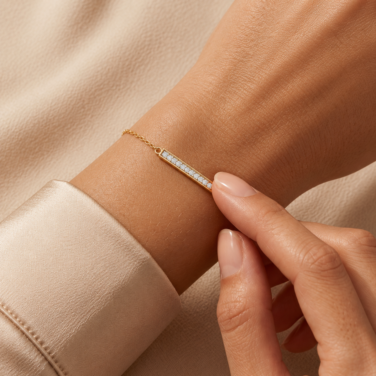 Yellow-gold diamond bar bracelet, 0.10 ct, worn on a wrist with a nude-manicured hand touching the setting.